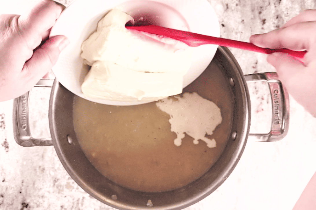 adding cream cheese to potato soup