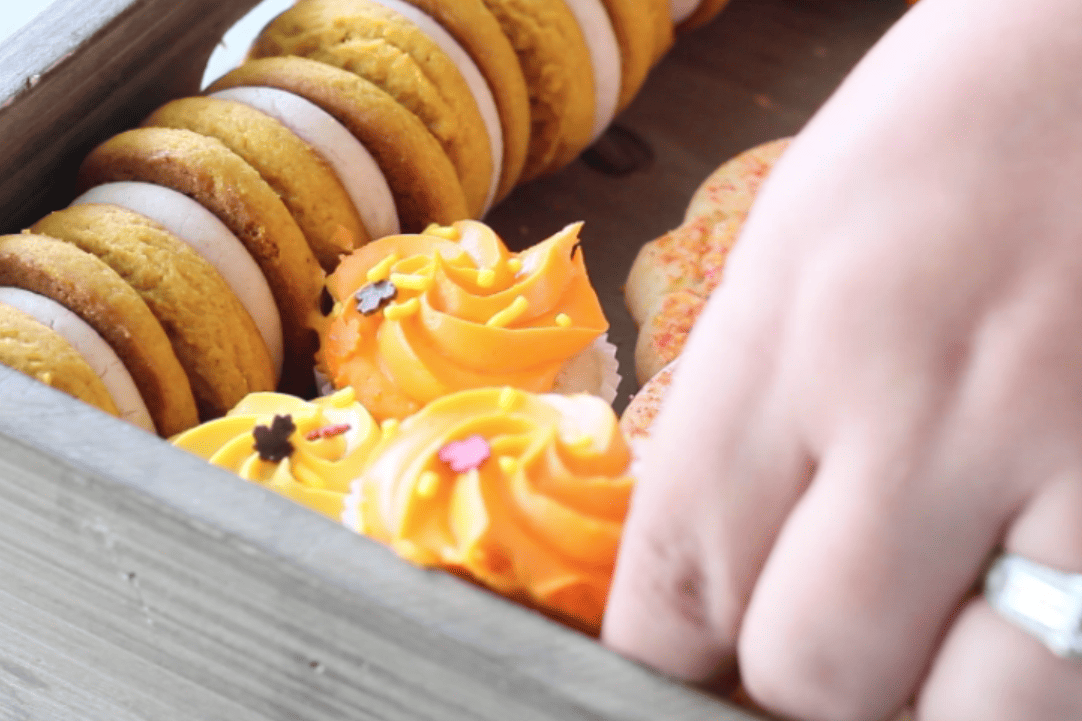 mini cupcakes with orange frosting being added.