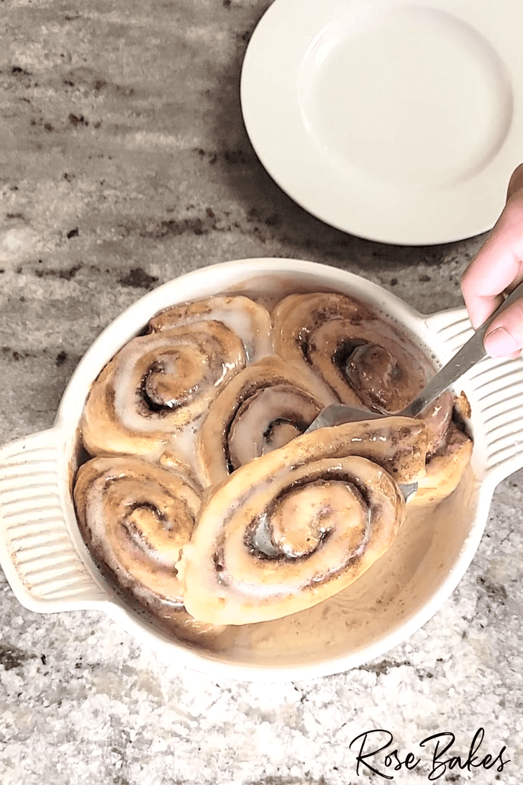 Cinnamon roll being lifted out of the dish on a serving spatula